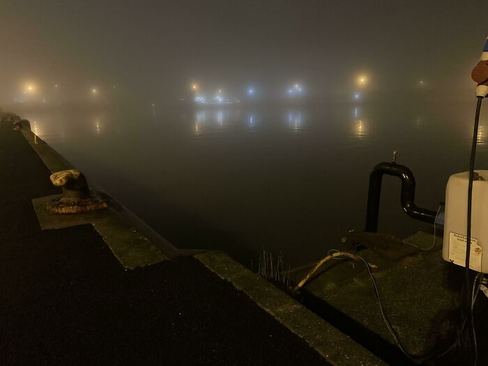 Foggy harbor at night with eerie reflections over deep water
