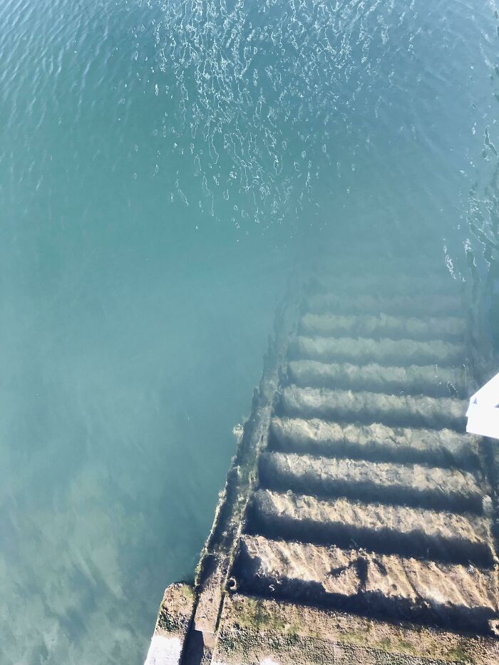 Underwater stairs covered in algae descending into clear deep water