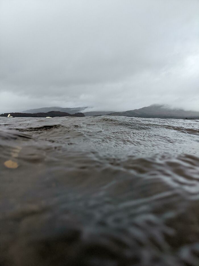 Dark, rippling deep water with obscured mountainous background under cloudy sky