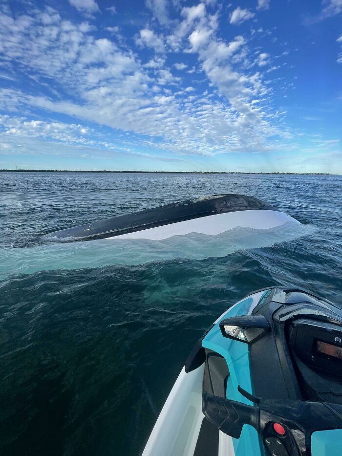 Upside down boat visible in deep-water sea near jet ski