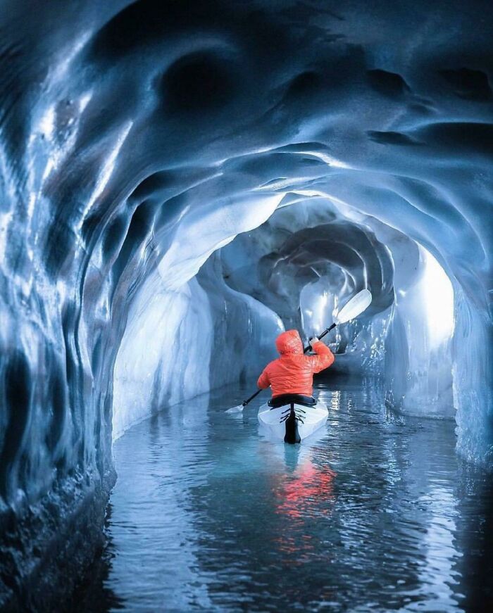Kayaker paddling inside an icy deep-water cave tunnel