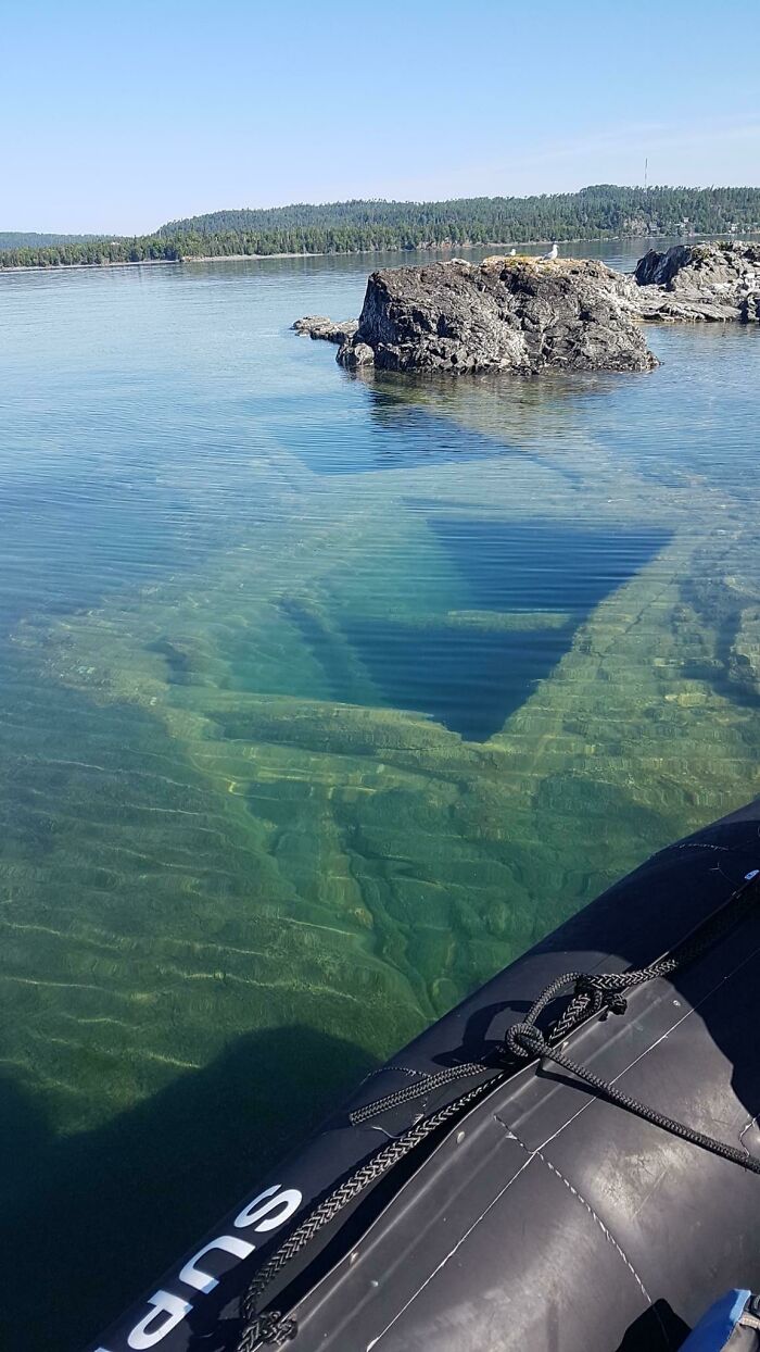 Underwater shipwreck partially visible near rocky shoreline