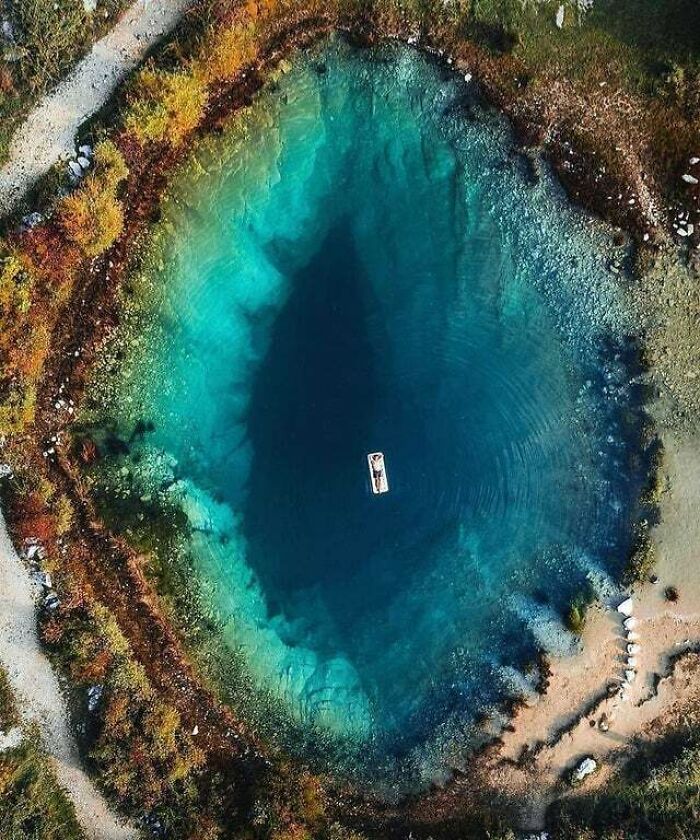 Aerial view of a deep blue lake with a small boat and clear water