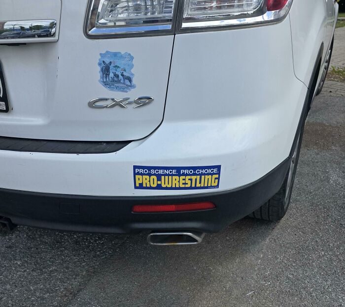A blue bumper sticker supporting science choice and pro-wrestling on a white car.