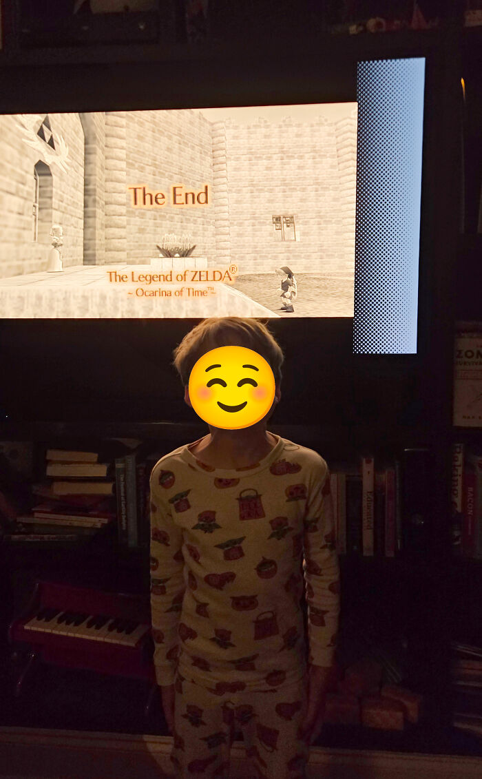 Child standing happily in front of a TV displaying The End of Zelda, showing memorable dads moments.