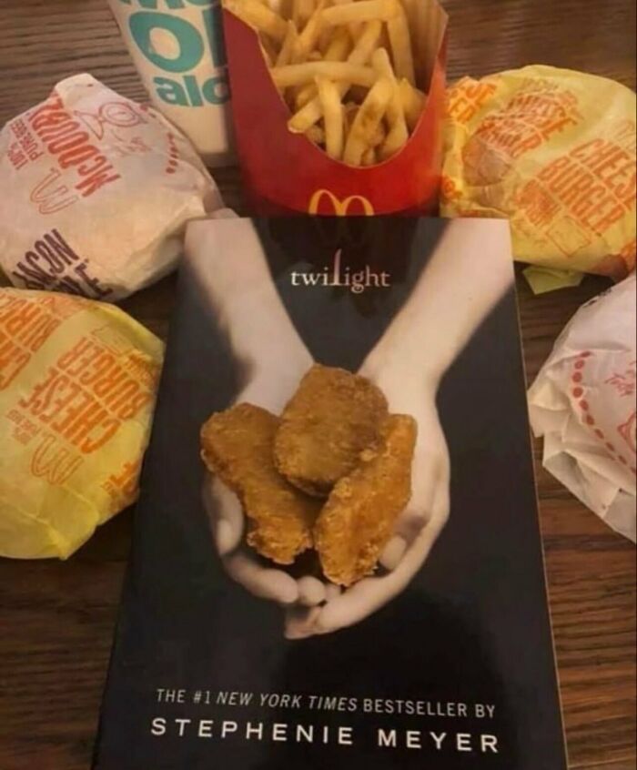 Weird and funny photo showing chicken nuggets placed over the hands on a Twilight book cover with fast food around.
