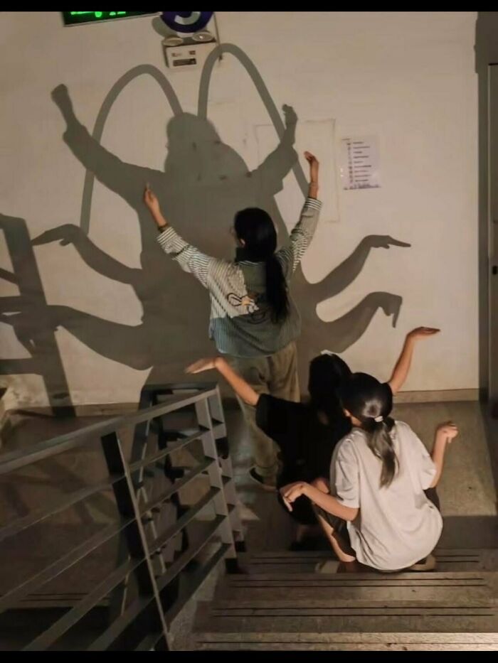 Weird photos of people making shadows that look like a giant bug on the wall.