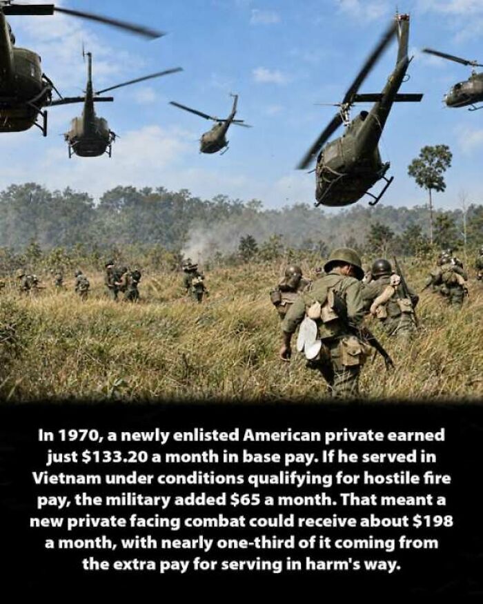Military helicopters flying over soldiers in a grassy field during a combat operation.