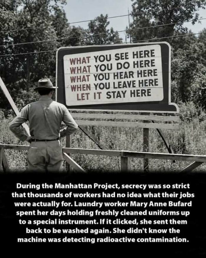 A man standing in front of a secrecy sign from the Manhattan Project, an interesting history moment.