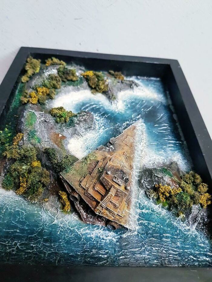 Miniature diorama of a pyramid structure surrounded by water and greenery