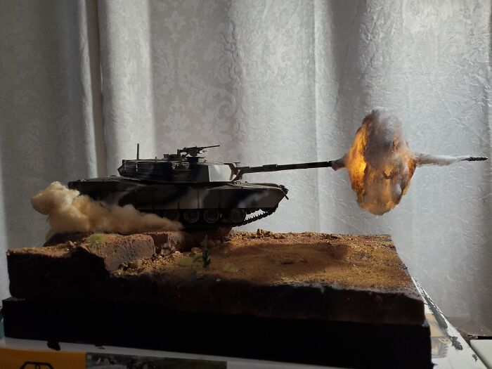 Miniature tank model firing with smoke and flame effects on diorama base