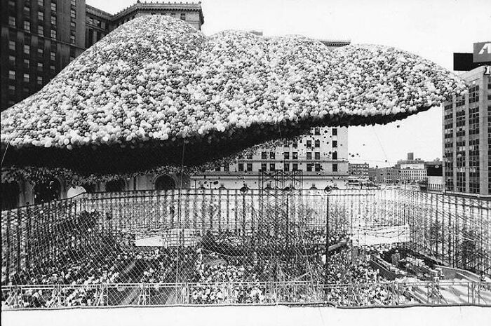 Black and white photo of large balloon cluster above city street event