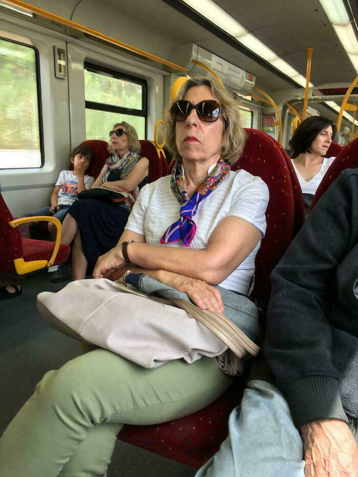 Woman with sunglasses sitting on public transit surrounded by passengers