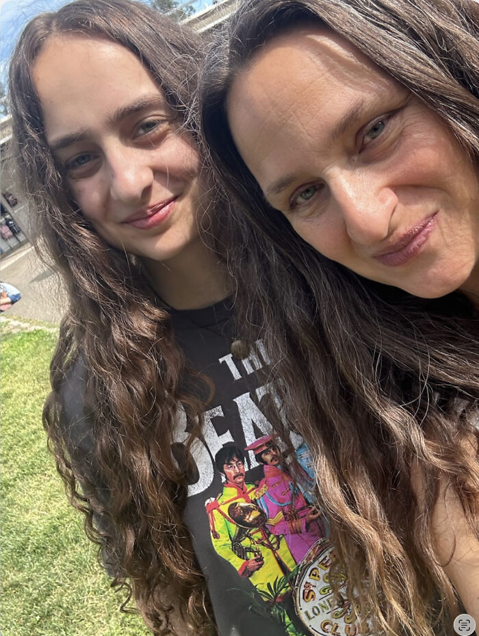 Two women smiling with one wearing The Beatles graphic shirt outdoors
