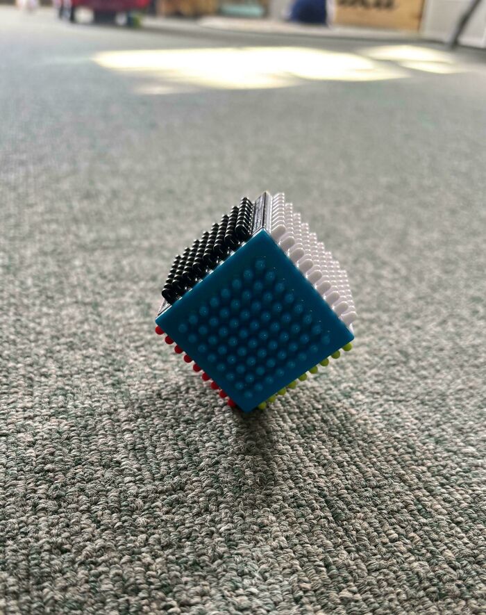 Cube toy standing on one corner on a carpeted floor
