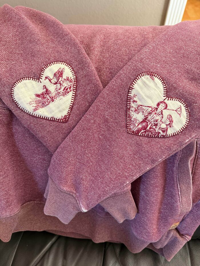 Heart patches repaired on a pink sweatshirt sleeves showing creativity to save money.