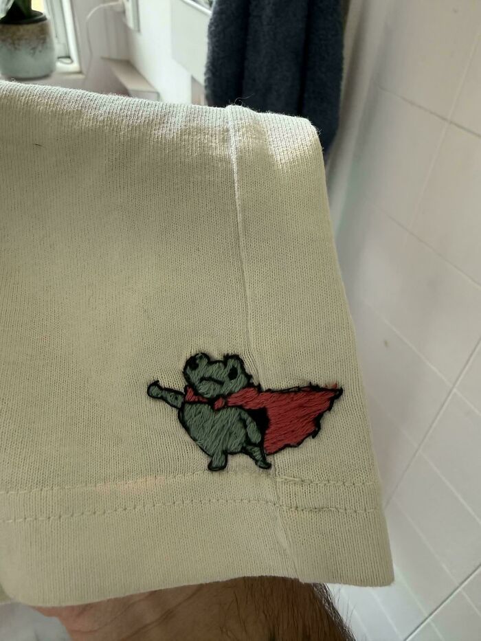 A small embroidered frog wearing a red cape showing creativity to save money.