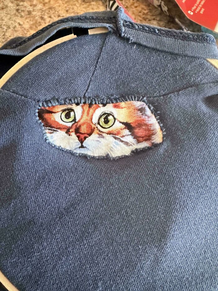 Cat face fabric patch visible through a hole in blue clothing showing creativity to save money
