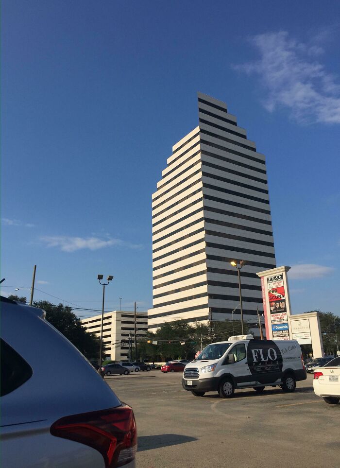 Tall building with striped windows in a city parking lot glitch