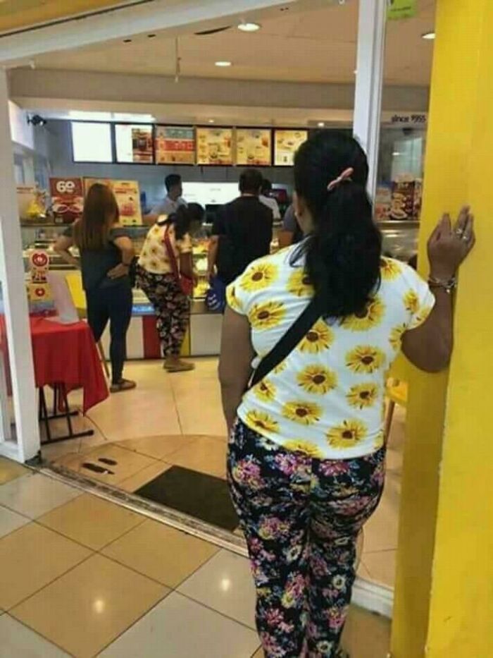 Woman wearing sunflower and floral patterns standing outside food counter glitch