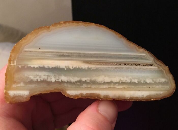 Hand holding a translucent layered geode stone resembling a natural glitch in crystals