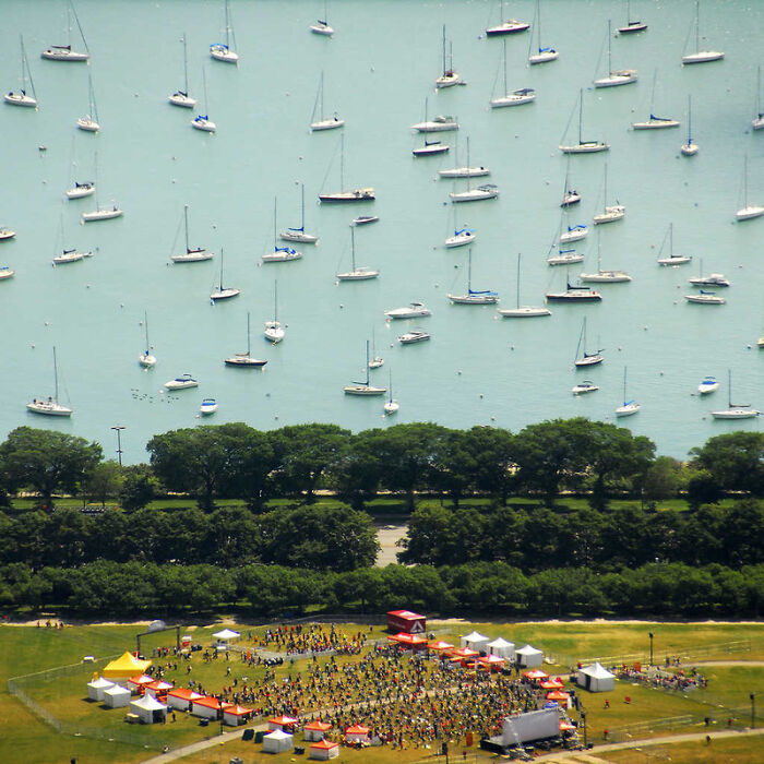 Aerial view of boats anchored in water with crowds near the shore