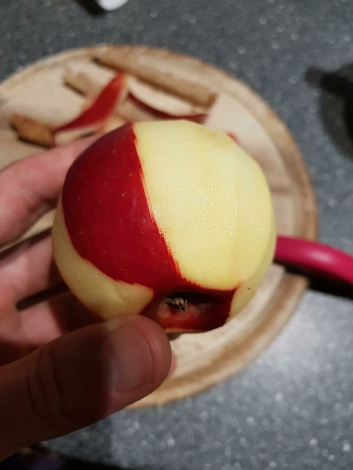 Hand holding a half-peeled red apple showing glitch-like pattern