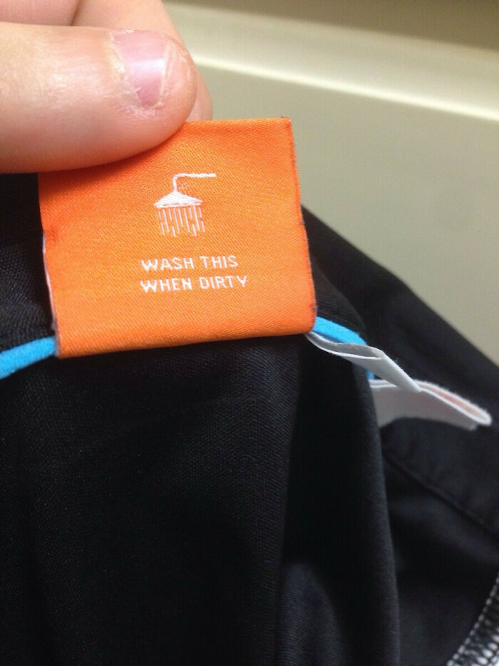 Orange shirt tag with confusing labels saying wash this when dirty under a shower icon.