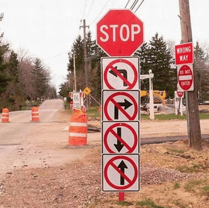 A confusing traffic sign post with a stop sign and multiple contradictory directional prohibition symbols