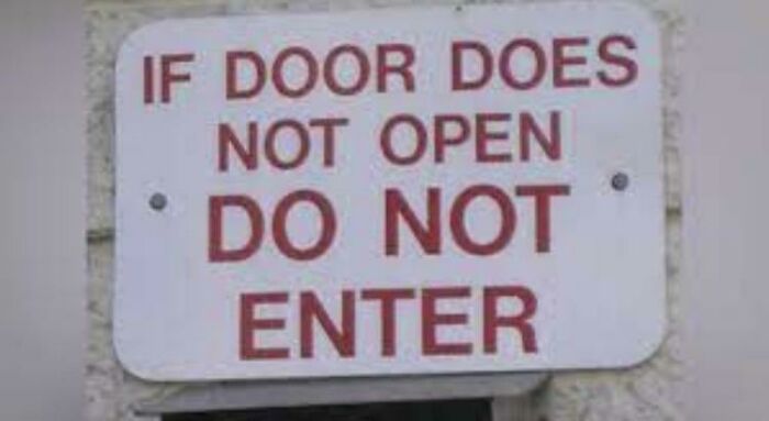 A confusing sign on a door stating 'IF DOOR DOES NOT OPEN DO NOT ENTER'.