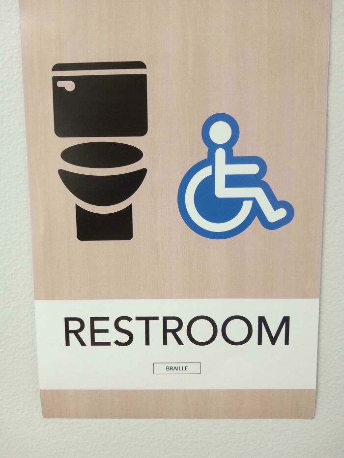 An accessible restroom sign featuring confusing labels instead of actual Braille dots