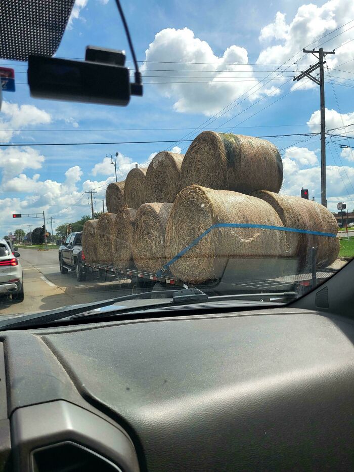 Overloaded trailer carrying massive round hay bales representing towing gone wrong.
