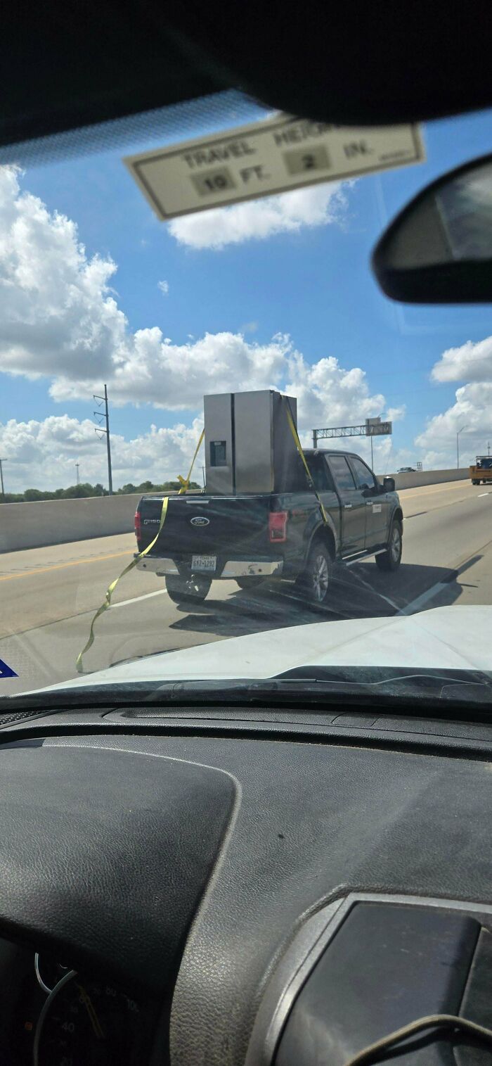 Pickup truck driving down the highway carrying an insecurely strapped refrigerator in an example of towing gone wrong.