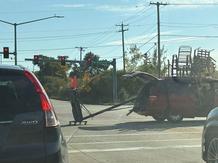 Red minivan dragging a basketball hoop behind it on the road as an example of towing gone wrong.