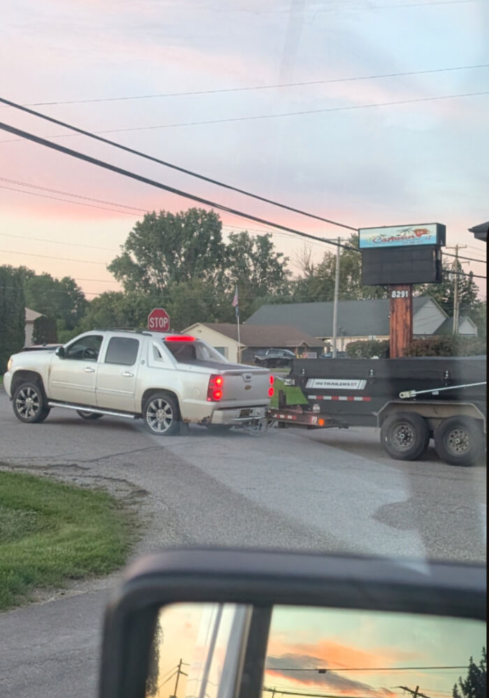White pickup truck tipping backward due to an overly heavy trailer in an example of towing gone wrong.