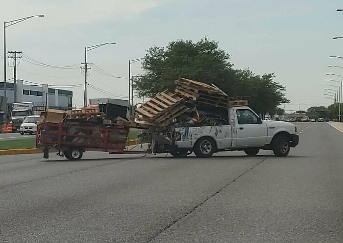 Overloaded pickup truck with wooden pallets depicting towing gone wrong on a highway.
