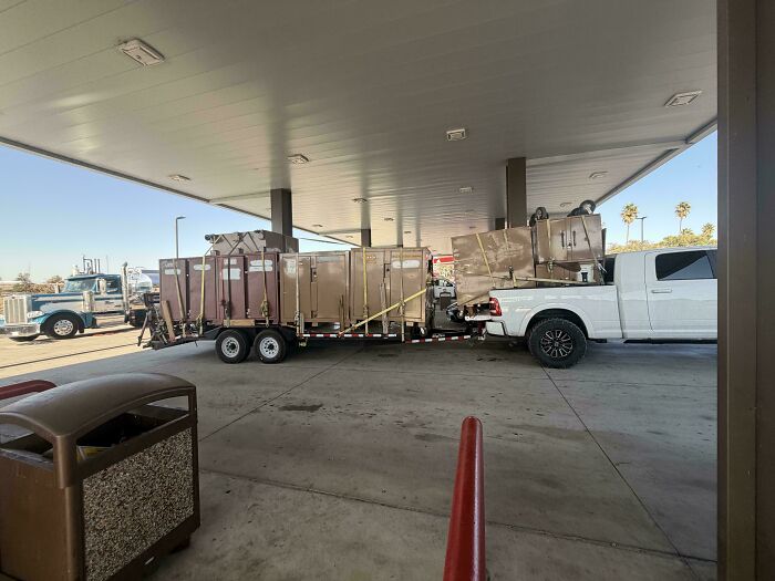 White pickup truck towing a trailer excessively loaded with large equipment showing towing gone wrong.
