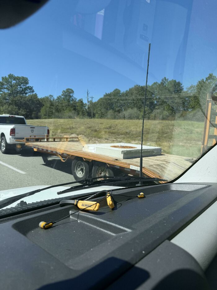 A white pickup truck towing a large flatbed trailer carrying a single concrete slab, an example of towing gone wrong.