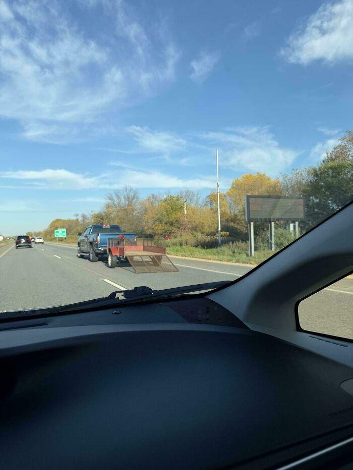 Pickup truck towing open trailer with ramp dragging down highway in towing gone wrong fail