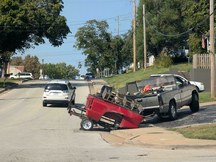 A red pickup truck bed trailer upside down on the street showing towing gone wrong.