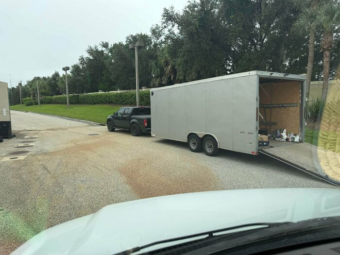 Small pickup truck attempting to pull an oversized enclosed cargo trailer on a road, a case of towing gone wrong.