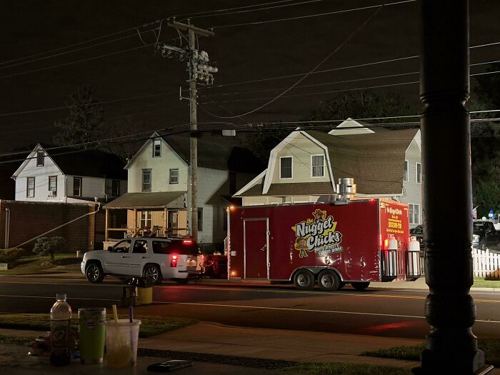 SUV towing an unlit red food trailer at night on a residential street, demonstrating unsafe towing gone wrong.
