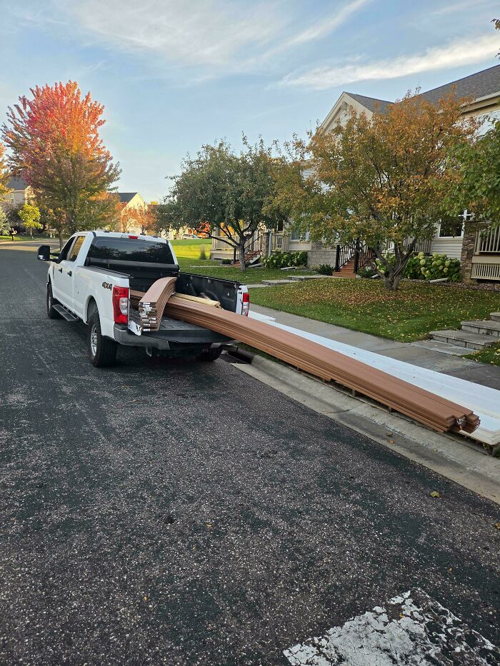 A pickup truck overloaded with extremely long wooden boards, illustrating towing gone wrong.