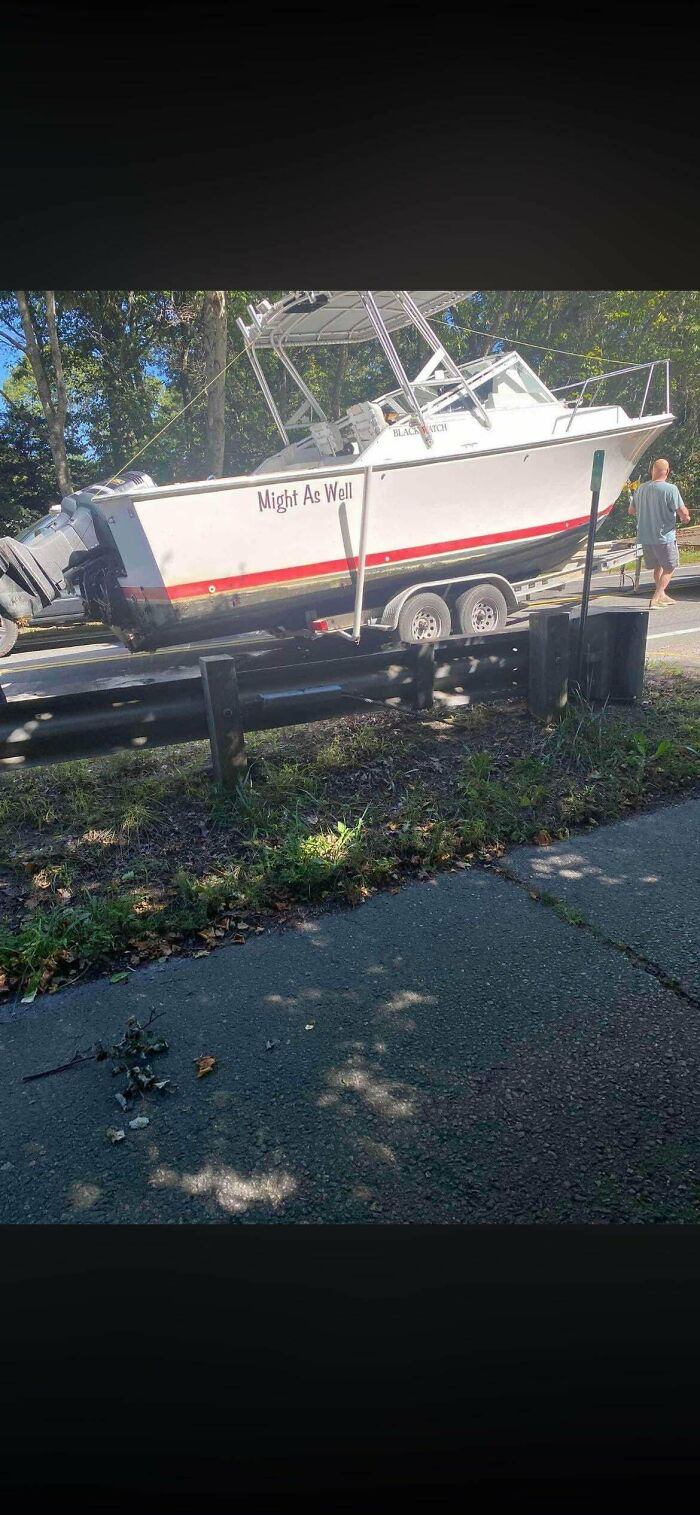 A white boat slipped partially off its trailer onto the road barrier in a case of towing gone wrong.