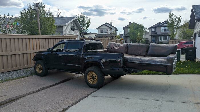 A black pickup truck carrying a huge sofa in its bed, an example of towing gone wrong.