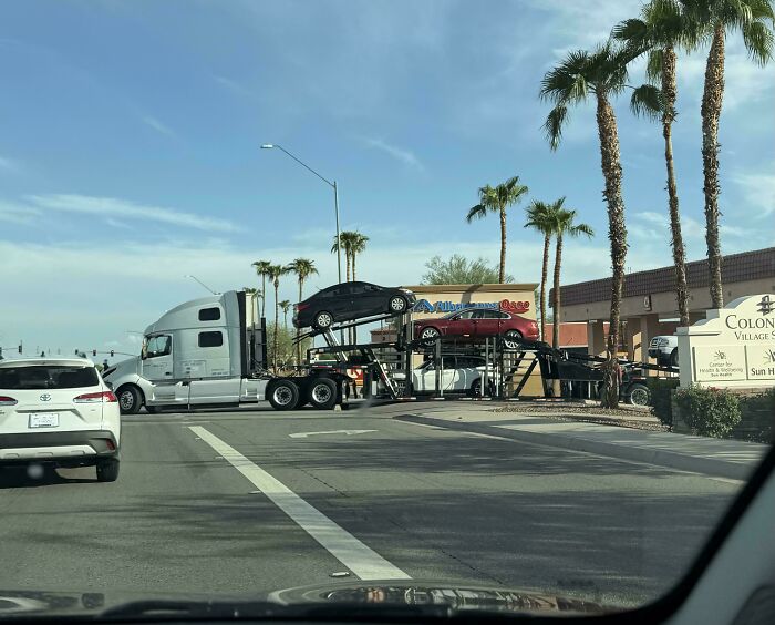 Large car carrier semi truck driving on city street, example of towing gone wrong hazards.