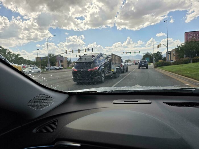 Car severely tilted sideways while pulling a trailer, showcasing towing gone wrong on the road