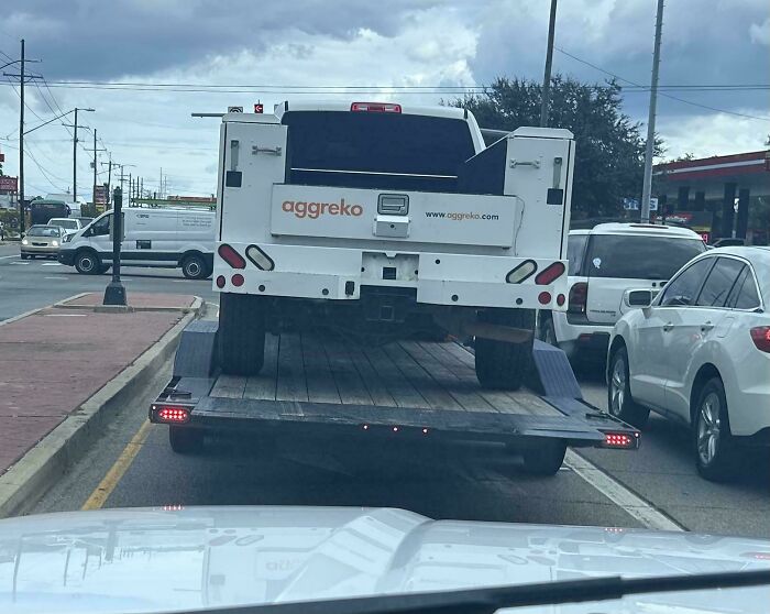 Large utility vehicle loaded incorrectly on a flatbed trailer in a towing gone wrong situation