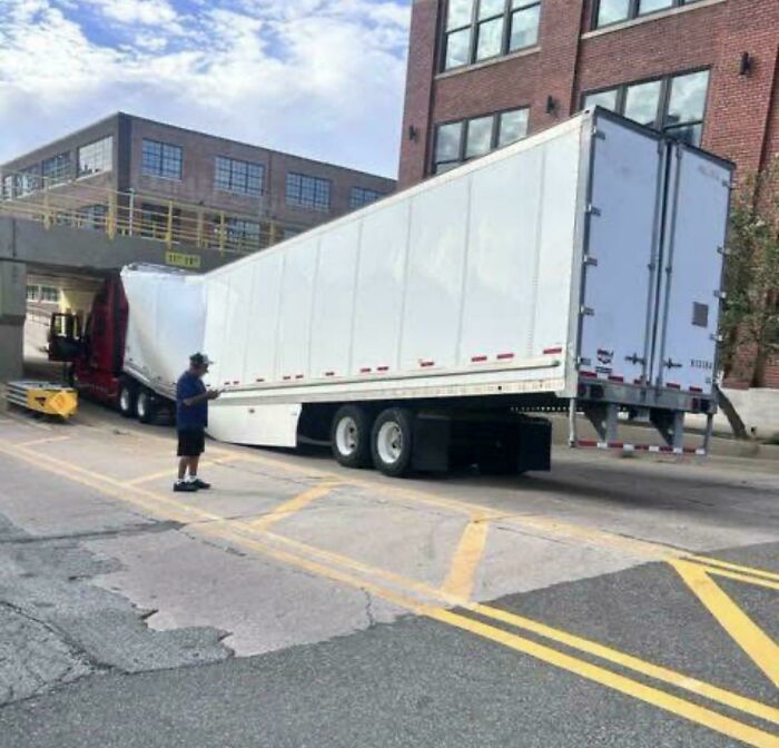 Large semi truck trailer bent completely in half under a low bridge clearance, a disaster of towing gone wrong.