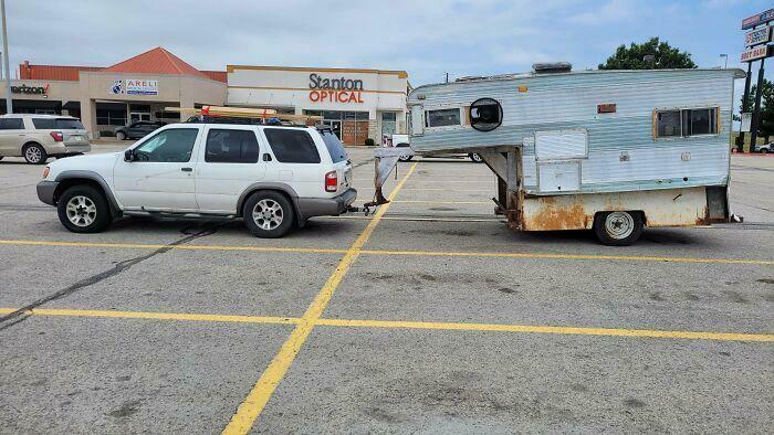 White SUV pulling a makeshift homemade camper trailer, showing a funny example of towing gone wrong.